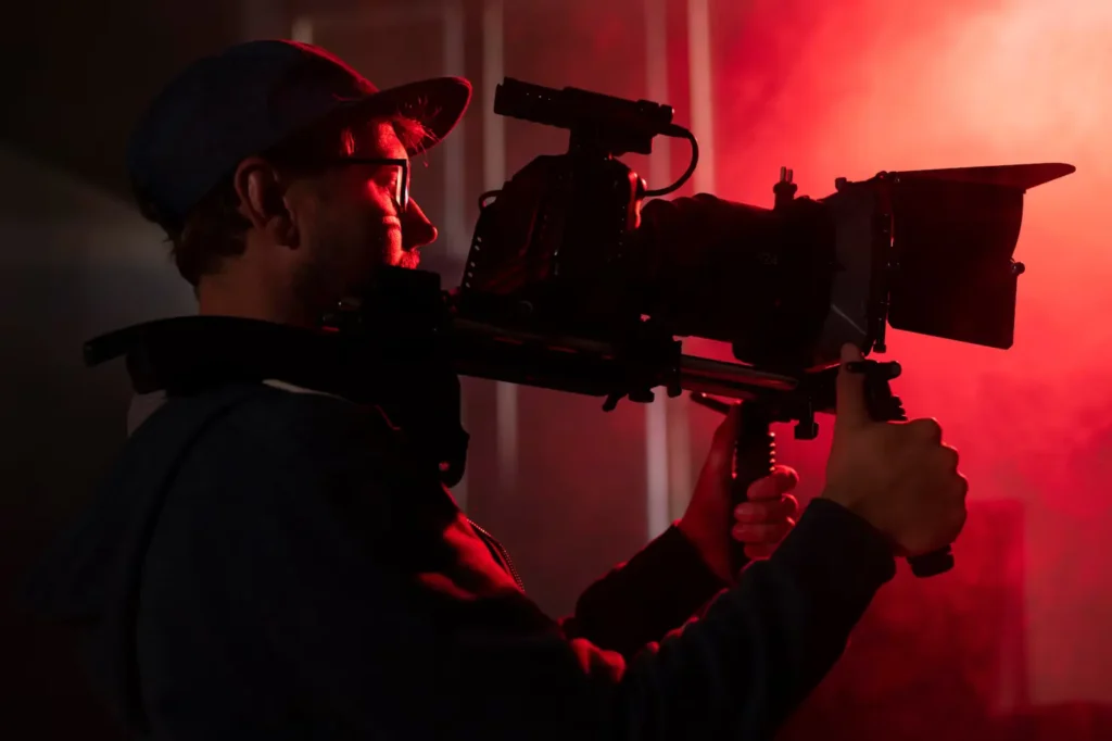Videographer filming under red studio light — content creation and production by Flinzap